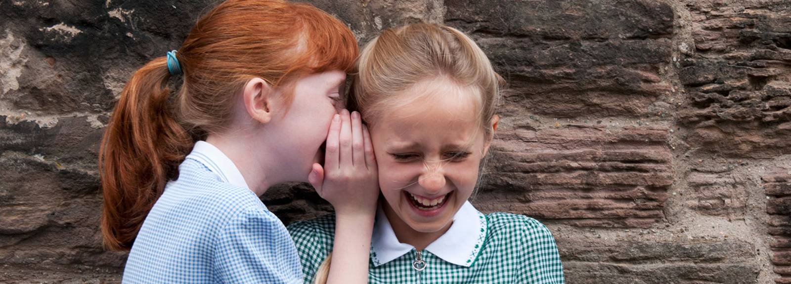two girls whispering and laughing